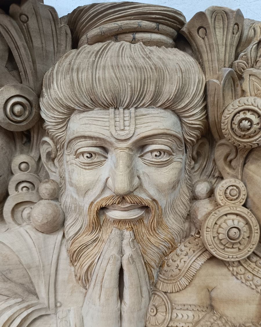 The sage Bhrigu, carved in kumbil wood: heavy lids, deep forehead lines, a long beard and hands joined in namaskara.